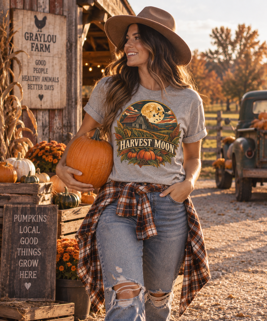 Woman wearing the Harvest Moon barn tee in a rustic autumn farm setting