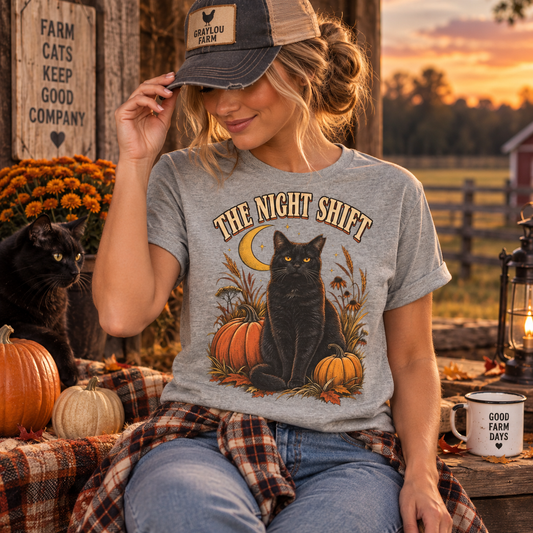 Woman wearing The Night Shift barn cat tee in a rustic fall farm setting